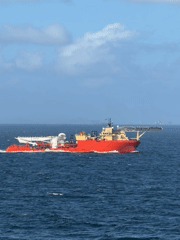 Offshore support vessel transits Gulf waters near drilling platform