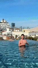 Man poses with drink in Madrid rooftop pool