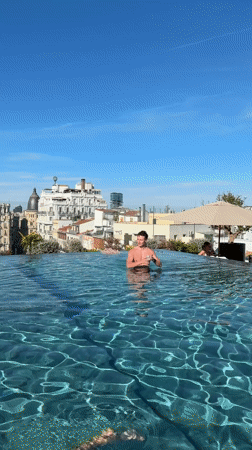 Man poses with drink in Madrid rooftop pool
