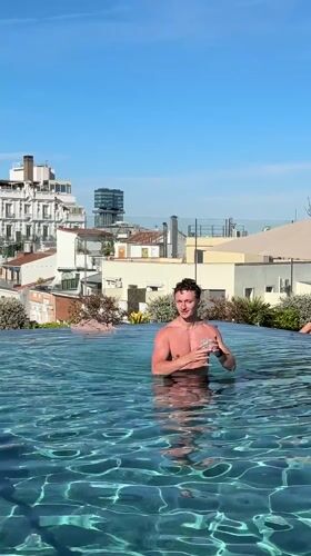 Man poses with drink in Madrid rooftop pool