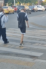 Pedestrians cross urban intersection during afternoon hours