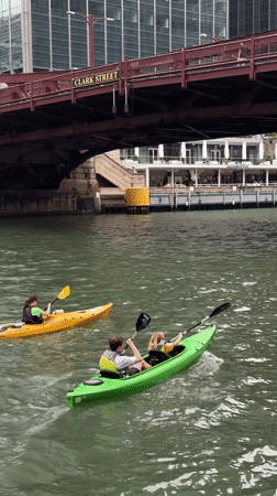 Kayaks and a motorboat navigate the Chicago River on a cloudy day