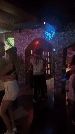 Couples dance in crowded Bangkok bar with tropical decor