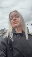 Woman in black trench coat photographed on Amsterdam street