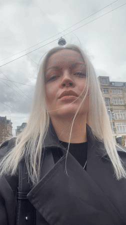 Woman in black trench coat photographed on Amsterdam street