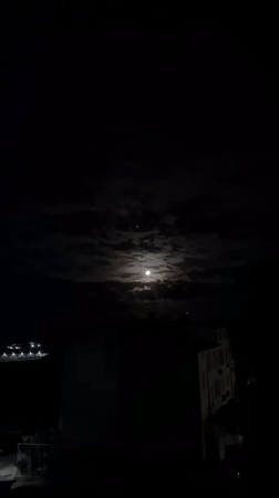 Full moon illuminates cloudy night sky over Burgas, Bulgaria