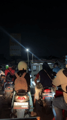 Motorcyclists wait at nighttime intersection in Tangerang, Indonesia