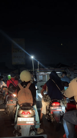 Motorcyclists wait at nighttime intersection in Tangerang, Indonesia