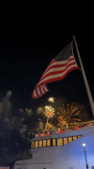 Fourth of July fireworks over Miami, flags flying from a boat