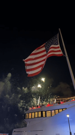 Fourth of July fireworks over Miami, flags flying from a boat