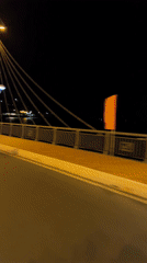 Motorcycles cross illuminated bridge in Nha Trang at night