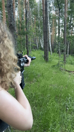Woman practices rifle shooting in Russian forest near Vasilyevo