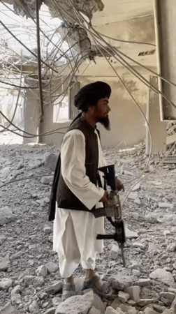 Men survey building damage aftermath in Mandisar, Afghanistan