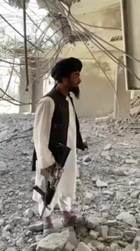 Men survey building damage aftermath in Mandisar, Afghanistan