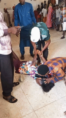 Woman on floor assisted by bystanders in public space