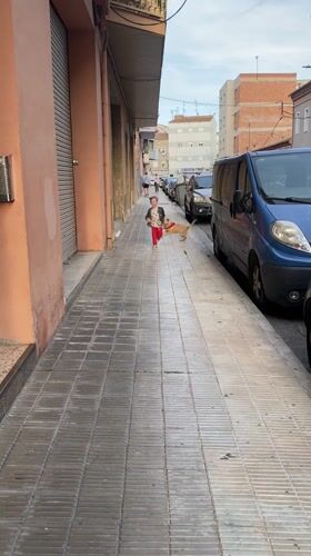 Boy runs with dog on Lleida sidewalk