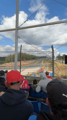 Trackside at a Formula 1 race, crowds and cars in action