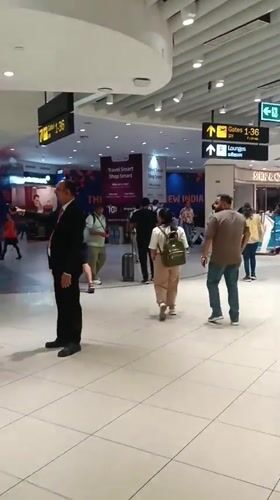Evening travelers move through busy New Delhi airport terminal
