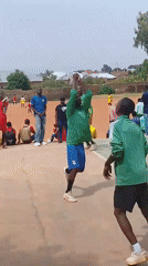 Outdoor volleyball game with uniformed teams and spectators