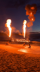 Fire performers spell NOMAD in flames at beach gathering
