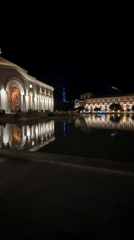 Nighttime documentation of illuminated neoclassical building complex with water features