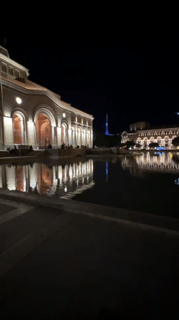 Nighttime documentation of illuminated neoclassical building complex with water features