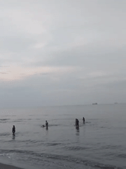 Beachgoers enjoy calm waters at Lhokseumawe coast under overcast skies