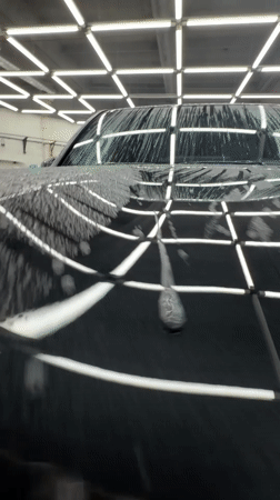 Detail shop polishing a dark blue car in Krasnoyarsk garage
