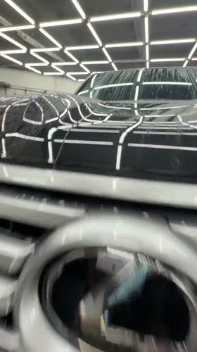 Detail shop polishing a dark blue car in Krasnoyarsk garage