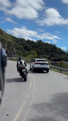Motorcyclist rides winding road followed by SUV in Argentina