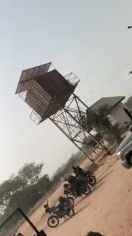 The video shows a dirt road with a water tower in the background. Three motorcycles are parked along the road. The camera is positioned inside a vehicle, possibly a jeep. The day appears sunny.