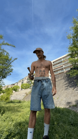 Tattooed street performer demonstrates kendama tricks in Lyon park