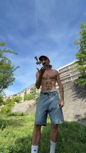 Tattooed street performer demonstrates kendama tricks in Lyon park