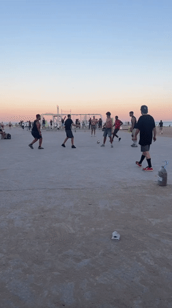 Casual soccer game played near Barcelona beach Tuesday evening