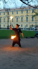 Fire performer juggles flaming torches in city square