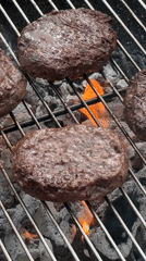 Burger patties grilling over charcoal flames captured in London
