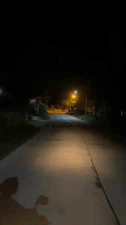 Motorcyclist travels illuminated road at night in Thong Sala