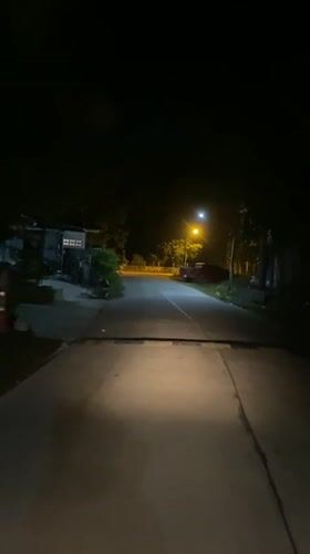 Motorcyclist travels illuminated road at night in Thong Sala