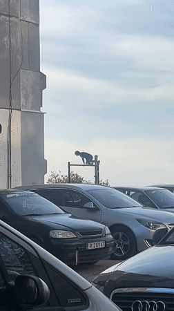 Person sits on billboard framework in Ruse parking lot
