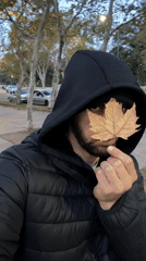 Man holds dried leaf over face on Buenos Aires sidewalk