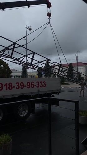 Crane offloading a metal truss from a flatbed in Prigorodnyi