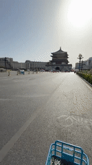 Cyclist rides toward traditional Chinese building in Lianhu District
