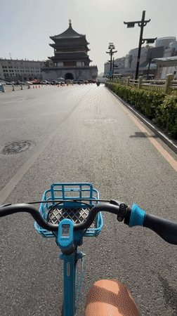 Cyclist rides toward traditional Chinese building in Lianhu District