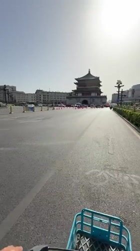 Cyclist rides toward traditional Chinese building in Lianhu District