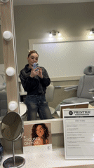 Woman Takes Mirror Selfie in Grey Room