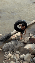 River play with an inner tube on a rocky Indonesian shoreline