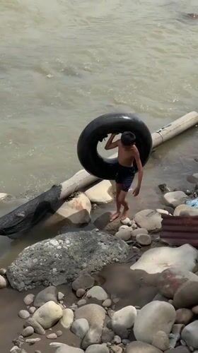 River play with an inner tube on a rocky Indonesian shoreline