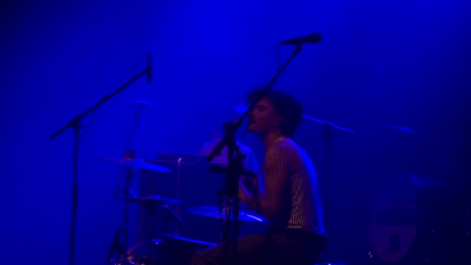 Live band performs under blue lights in Milan venue