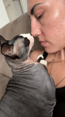 Woman holds Sphynx cat on couch in Netanya