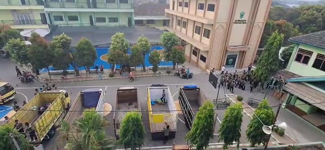 Uniformed group and yellow trucks staged at school complex